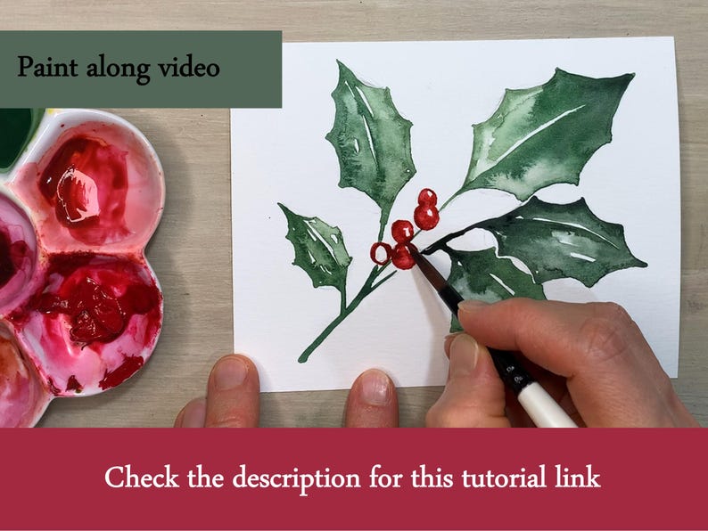 Pode incluir: Pintura em aquarela de azevinho com folhas verdes e bagas vermelhas. Uma m&atilde;o est&aacute; pintando as bagas com um pincel. O texto na imagem diz "Paint along video" e "Check the description for this tutorial link".