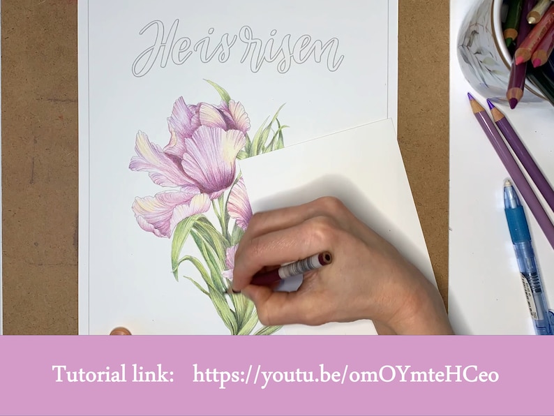 May include: A hand is colouring a drawing of pink tulips with green leaves. The drawing is on a white sheet of paper with the words "He is risen" written in cursive at the top. The tutorial link is "https://youtu.be/omOYmteHCeo".