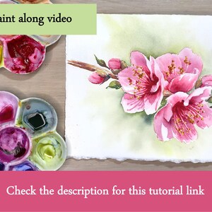 K&ouml;nnte beinhalten: Aquarellmalerei von rosa Kirschbl&uuml;ten auf einem Ast, mit gr&uuml;nen Bl&auml;ttern und Knospen. Das Gem&auml;lde befindet sich auf strukturiertem Papier. Zwei Farbpaletten mit verschiedenen Farben befinden sich im Bild. Der Text lautet "Paint along video" und "Check the description for this tutorial link."