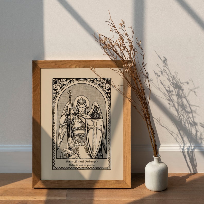 May include: A framed black and white print of an illustration of Saint Michael the Archangel. The image depicts the angel with wings, a sword, and a shield. The text below the image reads "Sancte Michael Archangele, Defende nos in proelio".