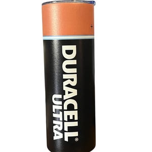 May include: A stainless steel tumbler designed to resemble a Duracell Ultra battery. The top section is orange, the middle has a blue stripe, and the bottom is black with the Duracell Ultra logo in white. The tumbler has a lid.