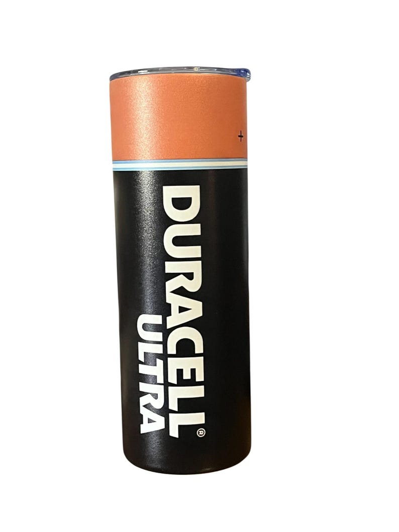 May include: A stainless steel tumbler designed to resemble a Duracell Ultra battery. The top section is orange, the middle has a blue stripe, and the bottom is black with the Duracell Ultra logo in white. The tumbler has a lid.