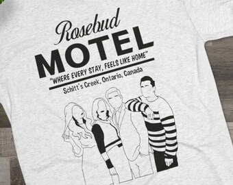 May include: Pale grey t-shirt with the words "Rosebud Motel" and the phrase "Where every stay, feels like home" and the location "Schitt's Creek, Ontario, Canada." The shirt also has a black and white line drawing of four people.