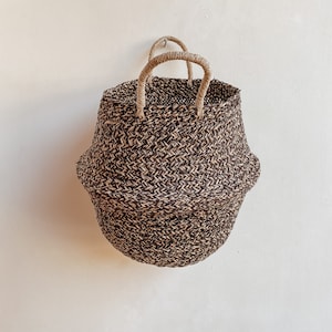 Peut inclure: Un panier rond en osier brun et noir avec deux anses. Le panier est fait de matériaux naturels.