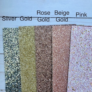 May include: Five strips of glitter fabric in different colors. From left to right: silver, gold, rose gold, beige gold, and pink.