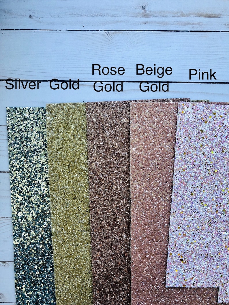 May include: Five strips of glitter fabric in different colors. From left to right: silver, gold, rose gold, beige gold, and pink.