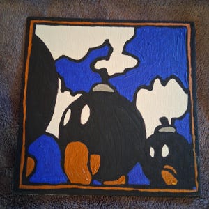 Puede incluir: Arte en lienzo cuadrado con un diseño de bomba de dibujos animados. La obra de arte utiliza los colores negro, blanco, azul y naranja. El fondo es azul con formas blancas en forma de nube. Las bombas son negras con ojos blancos y pies naranjas.