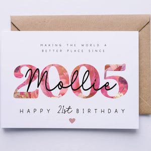 May include: A white birthday card with the text "Making the world a better place since 2005 Mollie Happy 21st Birthday" in black font. The numbers "2005" are filled with a floral pattern, and a pink heart is at the bottom.