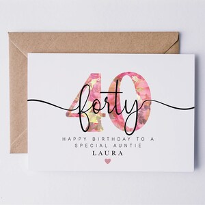 May include: A white card with a pink floral design in the number "40" with the text "forty" in black cursive script. The card reads "Happy Birthday to a Special Auntie Laura" with a pink heart.