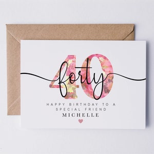 May include: A white card with a pink floral design in the shape of the number 40. The text "forty" is written in black cursive script over the floral design. The text "Happy birthday to a special friend Michelle" is written below the number 40.
