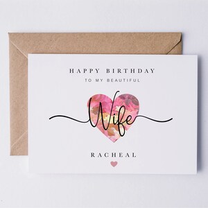 May include: A white card with the text "Happy Birthday to my beautiful Wife" and a pink floral heart with the word "Wife" inside. The name "Rachel" is printed below the heart.