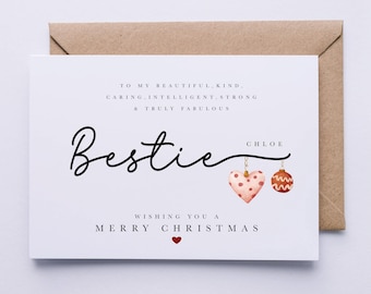 Może przedstawiać: Biała kartka świąteczna z ręcznie napisanym tekstem: "To my beautiful, kind, caring, intelligent, strong & truly fabulous Bestie Chloe Wishing you a Merry Christmas". Na kartce widnieje czerwone serce i dwie ozdoby choinkowe, jedna w kształcie serca, a druga w kształcie kuli.
