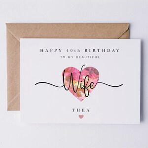 May include: A white card with the text "Happy 40th Birthday to my beautiful Wife Thea" with a pink floral heart graphic.
