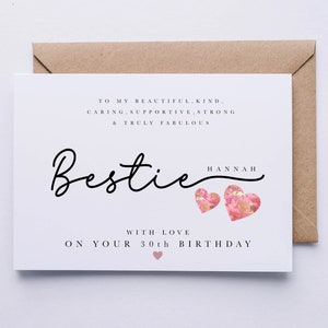 May include: A white greeting card with the word "Bestie" in cursive script, accompanied by the name "Hannah". The card includes text that reads "To my beautiful, kind, caring, supportive, strong & truly fabulous" and "With love on your 30th birthday". Two pink hearts are also featured.