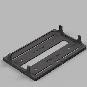 May include: A black plastic 3D printed stand with the text "UCO + Fiber" and "KTS Craft Labs" printed on it. The stand has two vertical supports on either side.