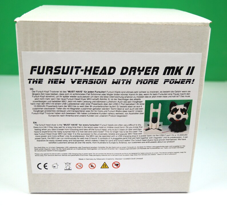 K&ouml;nnte beinhalten: Eine wei&szlig;e Box mit einem schwarz-wei&szlig;en Bild eines pelzigen Tierkopfes auf der Vorderseite. Die Box ist mit "Fursuit-Head Dryer MK II The New Version with More Power!" beschriftet. Der Text auf der Box ist sowohl in Englisch als auch in Deutsch. Die Box ist f&uuml;r ein Produkt, das Fursuit-K&ouml;pfe trocknet.