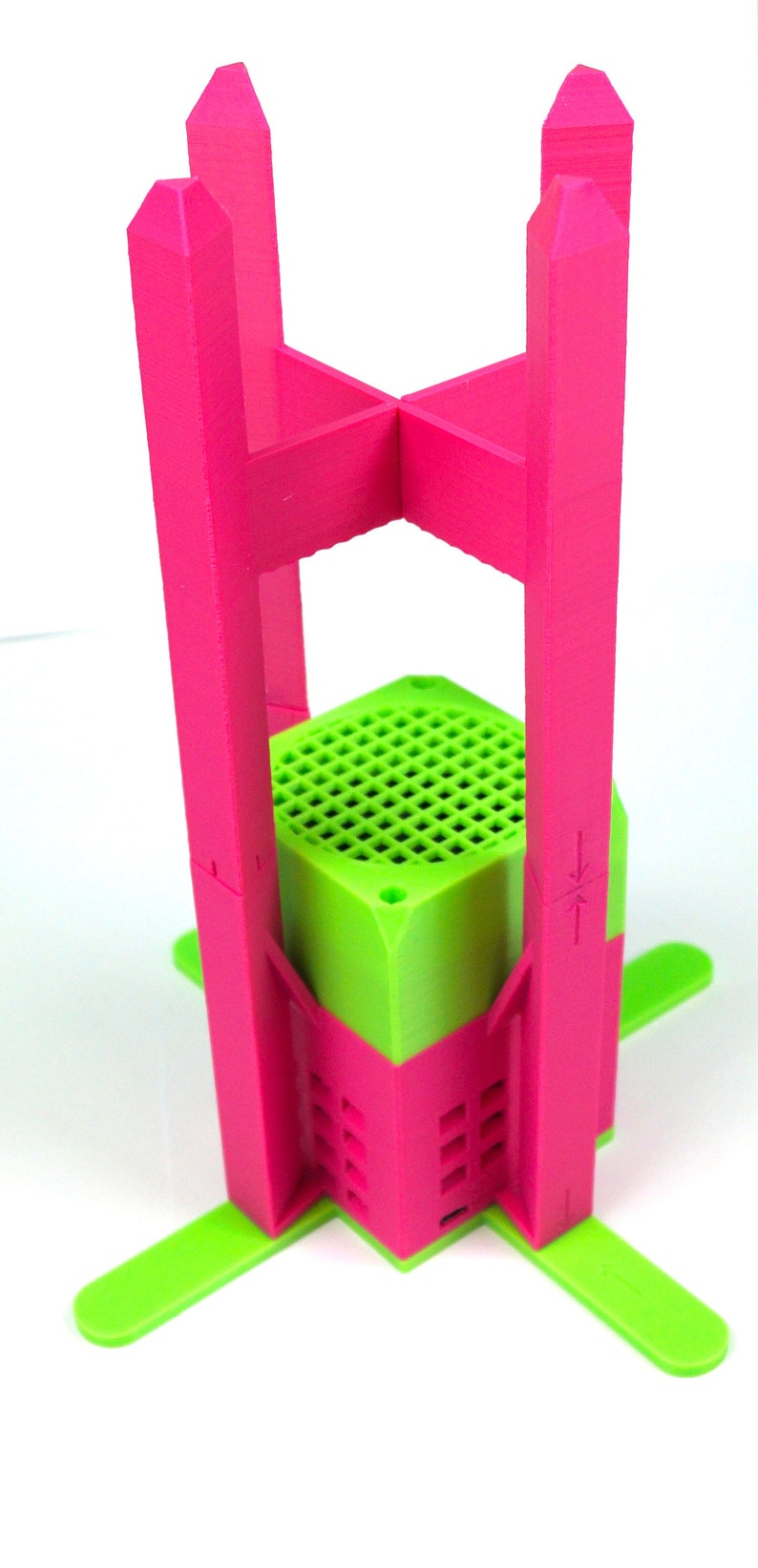 K&ouml;nnte beinhalten: Ein rosa und gr&uuml;ner 3D-gedruckter St&auml;nder mit sechseckiger Basis und vier hohen Beinen. Der St&auml;nder ist so konzipiert, dass er einen kleinen Gegenstand wie einen Lautsprecher oder eine Pflanze aufnehmen kann.