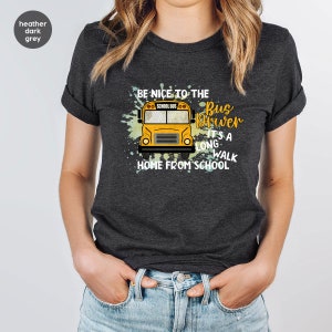 May include: Heather dark grey t-shirt with a yellow school bus graphic and the text "Be nice to the bus driver it's a long walk home from school".