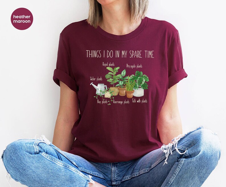 Peut inclure: Un t-shirt marron avec le texte "THINGS I DO IN MY SPARE TIME" et une liste d'activit&eacute;s li&eacute;es aux plantes, notamment "Repot plants", "Propagate plants", "Water plants", "Buy plants", "Rearrange plants", et "Talk with plants".