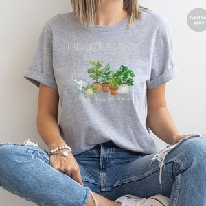 Peut inclure: T-shirt gris chin&eacute; avec le texte "Things I do in my spare time" et un graphique de plantes en pot. Le texte sous le graphique indique "Water plants, Repot plants, Arrange plants, Talk with plants."