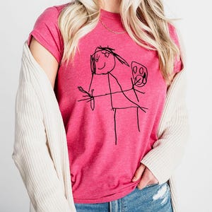 a woman wearing a pink shirt with a drawing on it