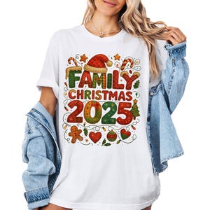 May include: White t-shirt featuring a vibrant Christmas design. The graphic reads "FAMILY CHRISTMAS 2025" with festive elements like a Santa hat, gingerbread man, and candy canes. The shirt has a relaxed fit and is suitable for casual wear.