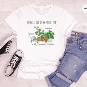 Peut inclure: T-shirt blanc avec un graphique de plantes et le texte "THINGS I DO IN MY SPARE TIME" avec les mots "Repot plants", "Propagate plants", "Water plants", "Buy plants", "Rearrange plants", et "Talk with plants" &eacute;crits sous le graphique.