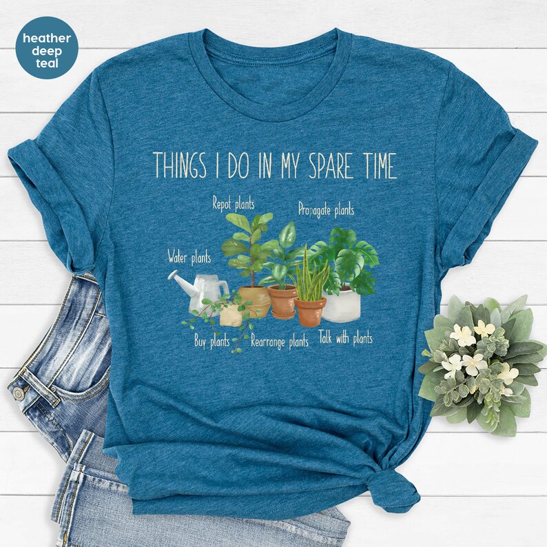 Peut inclure: Un t-shirt bleu sarcelle fonc&eacute; en coton m&eacute;lang&eacute; avec le texte "THINGS I DO IN MY SPARE TIME" et une liste d'activit&eacute;s li&eacute;es aux plantes, notamment "Arroser les plantes", "Rempotage des plantes", "Propager les plantes", "Acheter des plantes", "R&eacute;organiser les plantes" et "Parler aux plantes".