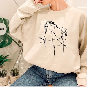 a woman wearing a sweatshirt with a drawing on it