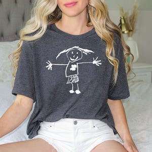a woman sitting on top of a bed wearing a t - shirt