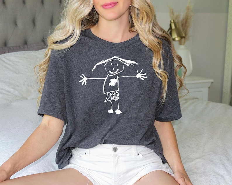 a woman sitting on top of a bed wearing a t - shirt