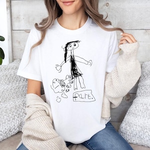 a woman sitting on a couch wearing a t - shirt with a drawing of a
