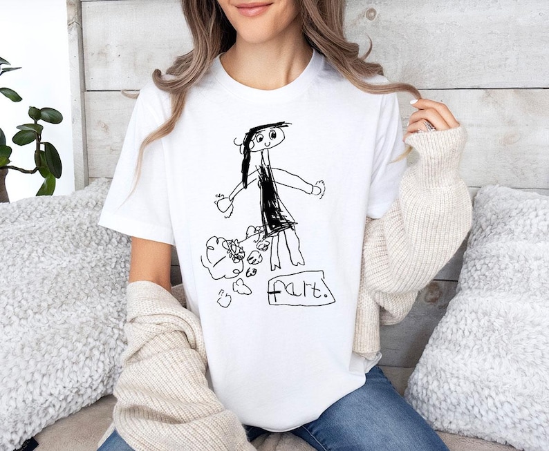 a woman sitting on a couch wearing a t - shirt with a drawing of a