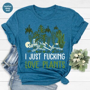 May include: A heather deep teal t-shirt with a skeleton surrounded by plants and the text "I JUST FUCKING LOVE PLANTS".