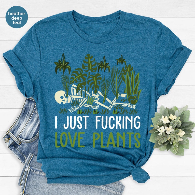 May include: A heather deep teal t-shirt with a skeleton surrounded by plants and the text "I JUST FUCKING LOVE PLANTS".