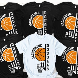May include: Five black t-shirts with white text and a basketball graphic. The text reads "JACQUELINE DOUGLAS #11". One white t-shirt with the same design.