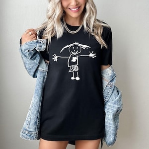 a woman wearing a black t - shirt with a drawing of a girl holding an