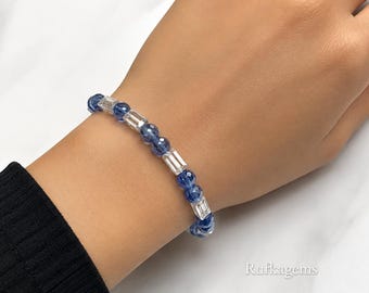 May include: A beaded bracelet featuring alternating round faceted blue beads and clear rectangular baguette-cut beads. The bracelet is worn on a wrist and includes the text Rufkagem in the bottom right corner of the image.