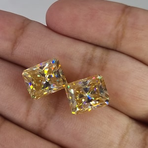 May include: Two square-shaped, yellow gemstones with a faceted cut. The gemstones have a rainbow-like iridescence.