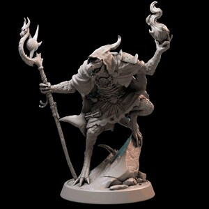May include: A grey, detailed miniature figurine of a reptilian humanoid creature wearing a robe and holding a staff and a flaming torch. The figurine is standing on a rocky base.