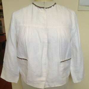 May include: A white linen jacket with a silver sequined trim around the collar and pockets.