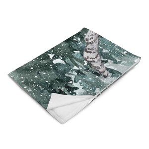 以下が含まれることがあります： 雪の降る森の風景が水彩画で描かれた、柔らかくふわふわの毛布。緑と白のカラーリングで、雪の結晶がさりげなく模様になっています。