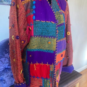 May include: A colorful patchwork jacket with a variety of textures and buttons. The jacket is made of different fabrics, including tweed, velvet, and corduroy. The jacket has a unique and eclectic style.