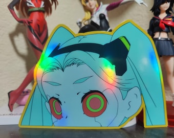 May include: A holographic sticker featuring a cartoon anime character with blue hair, red eyes, and a black headband. The sticker has a rainbow iridescent effect.