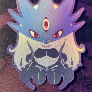 May include: A holographic sticker featuring a stylized anime character with a blue and purple mask, red eyes, and blonde hair. The character is wearing a black and white outfit with intricate details. The sticker has a glossy finish and is set against a purple background.