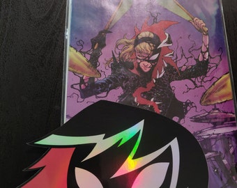 May include: Comic book cover with a character drumming, title "SPIDER" in white. A black and holographic sticker of a stylized mask is in the foreground. The comic is in a protective sleeve.