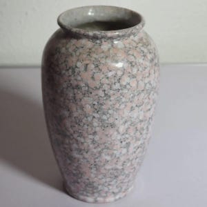 Könnte beinhalten: Eine gesprenkelte rosa-graue Keramikvase mit breitem Körper und schmalem Hals. Die Vase hat eine glatte, glänzende Oberfläche und einen hellgrauen Rand. Diese dekorative Vase eignet sich zum Präsentieren von Blumen oder als eigenständiges Akzentstück.
