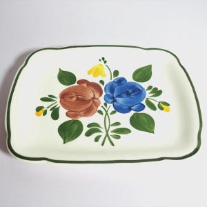 Peut inclure: Plat à servir rectangulaire en céramique crème, bordé de vert. Il présente un motif floral peint à la main avec des roses marron et bleues, des feuilles vertes et des touches de jaune. Décoratif.