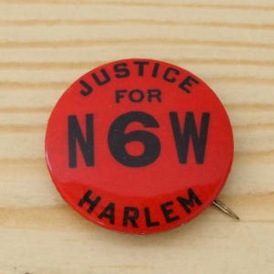 Könnte beinhalten: Ein runder roter Ansteckbutton mit fettgedrucktem schwarzem Text, der JUSTICE FOR N6W HARLEM lautet. Das Design zeigt das Wort JUSTICE in einem Bogen oben, das Wort FOR in der Mitte, die Zeichenfolge N6W mittig und HARLEM am unteren Rand.