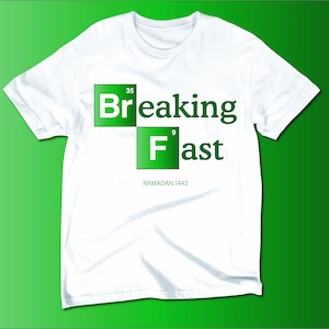 May include: White t-shirt with a green graphic design that says "Breaking Fast" with the word "Breaking" in a green square with the number "35" in the top right corner and the word "Fast" in a green square with the number "9" in the top right corner. The text "RAMADAN 1443" is below the graphic.